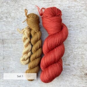 A tiny skein of pale coffee silk, a larger skein of dark honey coloured wool and a full skein deep madder red wool