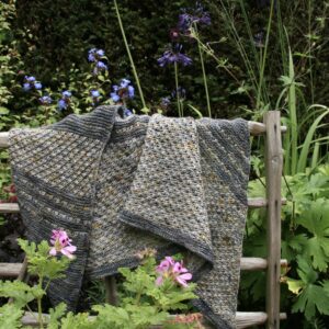 A grey shawl hanging on a chestnut hurdle