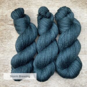 Three plump skeins of British wool in a moody grey blue