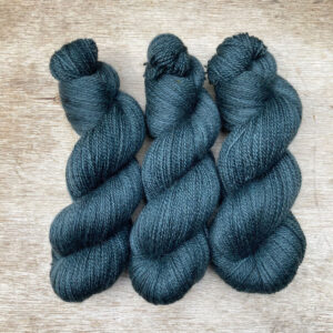 Three plump skeins of British wool in a moody grey blue