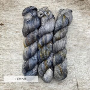 Three skeins of soft yarn in shades of silver, blue and gold