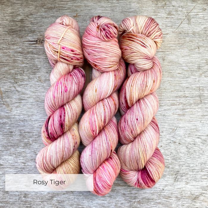 Three skeins of DK yarn in a creamy yellow speckled with dark red and pinks