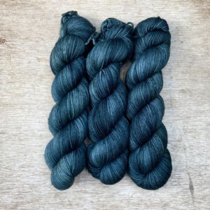 Three skeins of yarn in a grey stormy teal
