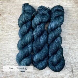 Three skeins of yarn in a grey stormy teal