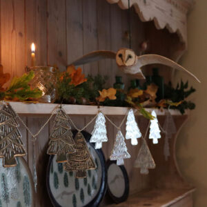 A papier mache owl flying over a string of silver trees