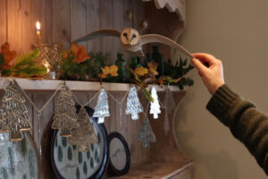 A papier mache owl flying over a string of silver trees