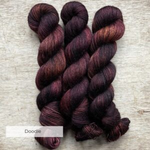 Three skeins of yarn in brown, dusty pink and bronze