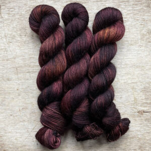 Three skeins of yarn in brown, dusty pink and bronze