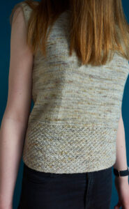 A young woman wearing a sleeveless top with a deep patterned hem