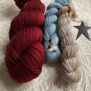 A full red skein of wool with a blue and stone coloured mini