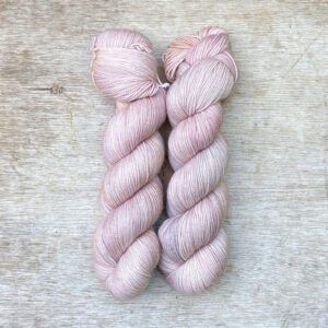 Two skeins of wool in pale pink, buff, grey and lilac