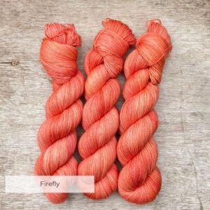 Three skeins of sock yarn in a deep peachy coral