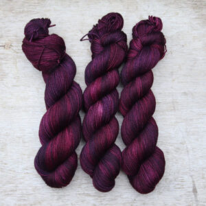Three skeins of sock yarn in deep, rich berry colours