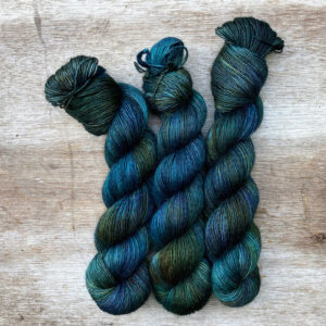 There skeins of softly fluffy yarn in shades of dark blue, green and teal