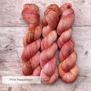 Three skeins of Merino & Silk in peach, coral and mulberry freckled with terracotta and gold