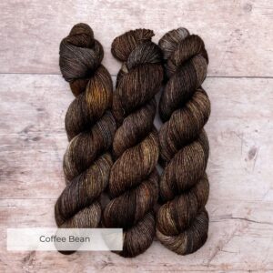 Three skeins of Merino & Silk wool in a bitter chocolate with splashes of grey and gold