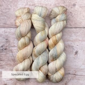 Three skeins of Merino & Silk wool in pale cream, pink and blue with bitter chocolate speckles