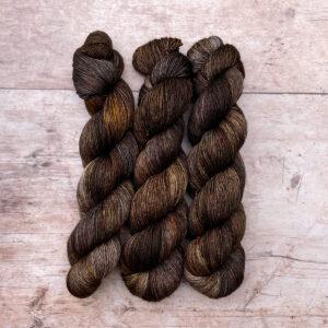 Three skeins of Merino & Silk wool in a bitter chocolate with splashes of grey and gold