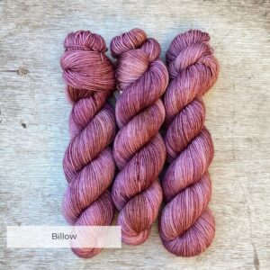 Three skeins of merino yarn in pinks and golds