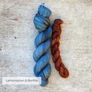 A full skein of merino sock yarn in shades of blue with splashes of gold and a smaller skein of toffee colour