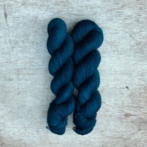 Two skeins of sock in a deep teal blue