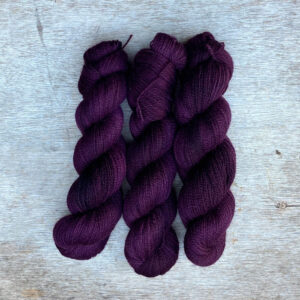 Three skeins of sock yarn in deep, rich berry colours