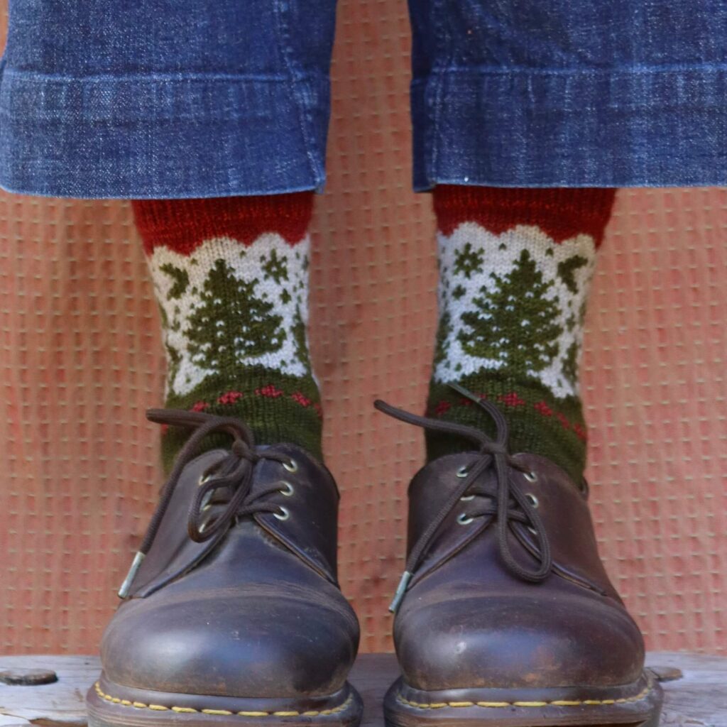 Hand knit socks with a colour work cuff of pine trees in a dark green with a red cuff