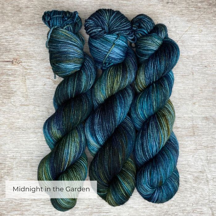Three skeins of plump DK wool in dark blues, emeralds and lime
