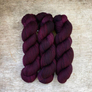 Three skeins of plump DK wool in deep plum purple