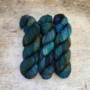 Three skeins of mohair sock yarn in dark blues, emeralds and lime