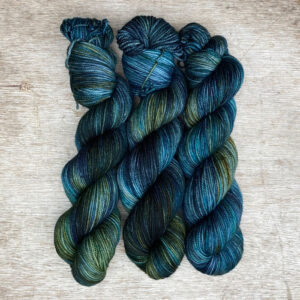Three skeins of plump DK wool in dark blues, emeralds and lime