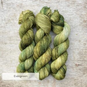 Three skeins of a wool and linen blended yarn in green with splashes of cream and flecks of gold