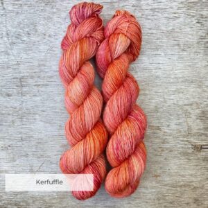 Two skeins of merino and linen yarn in shades of bright peach, shocking pink and orange