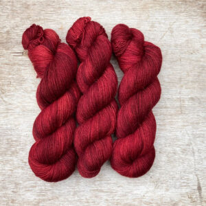 Three skeins of merino and mohair sock yarn in a deep, dark red