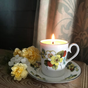 A teacup candle on a saucer with flowers