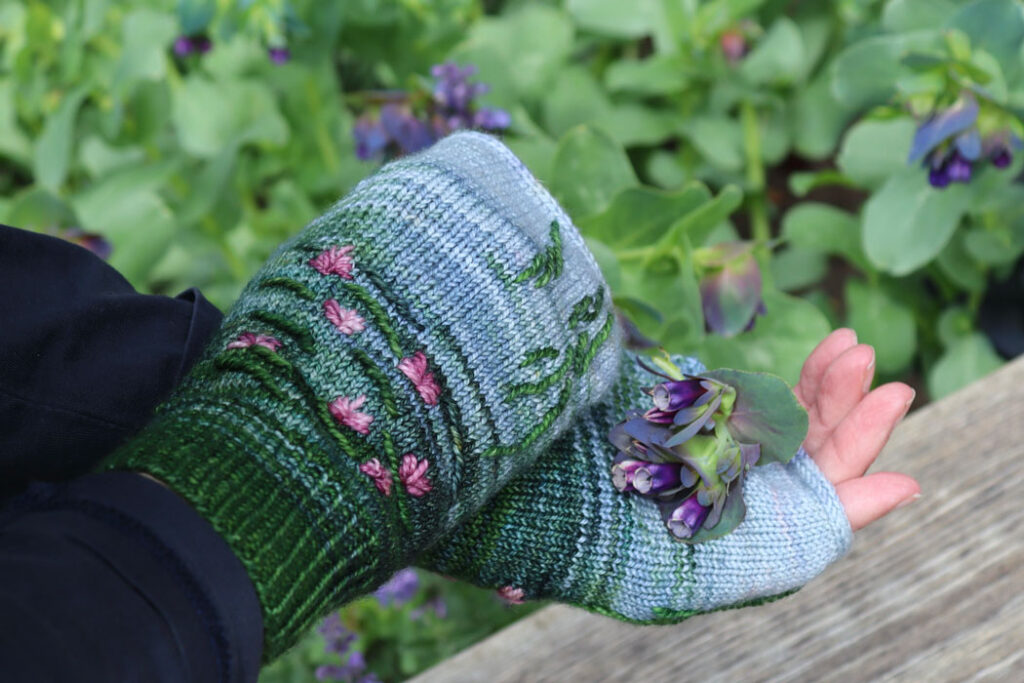Hands wearing Water Lily mittens and holding honeywort