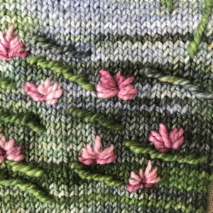 Pink water lilies embroidered on green and blue knitted mitten