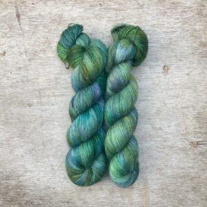 Two skeins of Merino Floof in pale green with splashes of moss , turquoise, gold and indigo