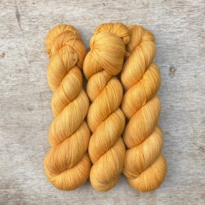 Three skeins of Classic Sock in a golden glowing yellow