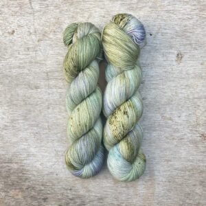 Two skeins of Classic Sock in pale green with splashes of moss and blue
