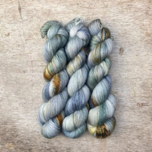 Three skeins of Merino Floof in shades of light blue and green with gold splashes