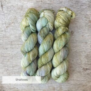 Three skeins of merino and silk lace in pale green with splashes of moss and blue