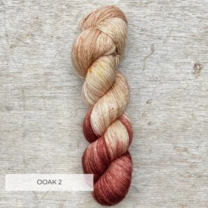 A single skein of Merino & Silk yarn one end a dark cranberry the other a creamy pink