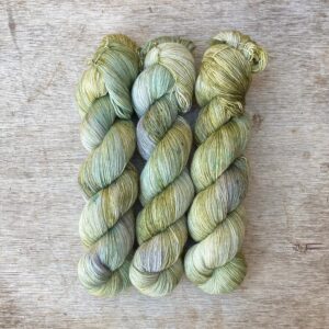 Three skeins of merino and silk lace in pale green with splashes of moss and blue