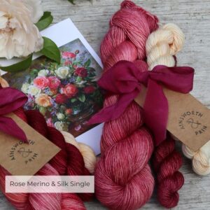 A single skein of rose pink Merino & Silk single with a mini skein in cream flushed oink and a deep crimson and burgundy