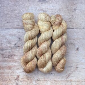 Three skeins of Merino & Silk single in the softest buttercream with splashes of cafe au lait