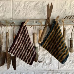 Two knitted cowls hung on a garden tool rail