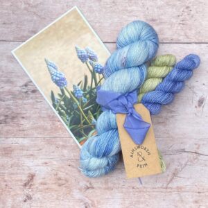 A full skein and two minis tied with a hand dyed ribbon and a photo of the flower that inspired their colours