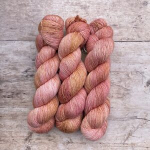 Three skeins of silky yarn in shades of pink and coral