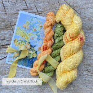 A skein of daffodil yellow merino and silk with two coordinating minis in green and apricot with the card that inspired them